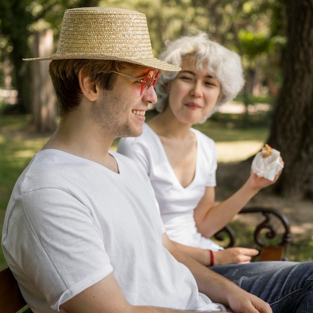 Pareja joven en el parque comiendo hamburguesas