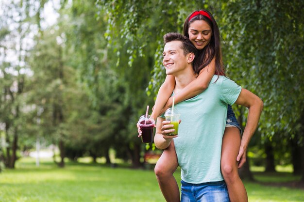 Pareja joven en el parque disfrutando de batidos saludables