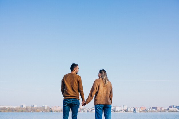 Pareja joven en el parque de pie junto al río