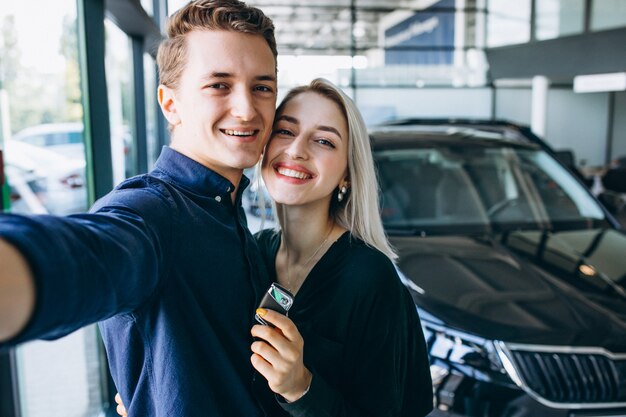 Pareja joven pasando un automóvil en una sala de exposición de automóviles