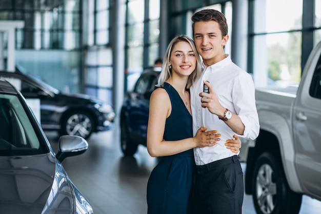 Pareja joven pasando un automóvil en una sala de exposición de automóviles