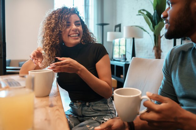 Pareja joven pasar un buen rato juntos mientras bebe una taza de café en casa.