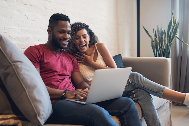 Pareja joven pasar tiempo juntos mientras usa una computadora portátil en casa. Nuevo concepto de estilo de vida normal.