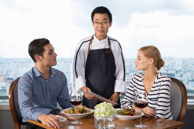 Pareja joven de pedido Platos Principales en restaurante