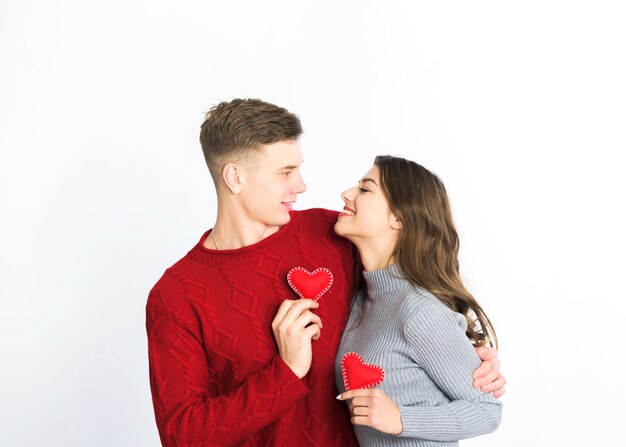 Pareja joven con pequeños corazones rojos en las manos