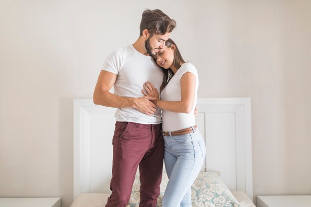 Pareja joven de pie en la cama y abrazar