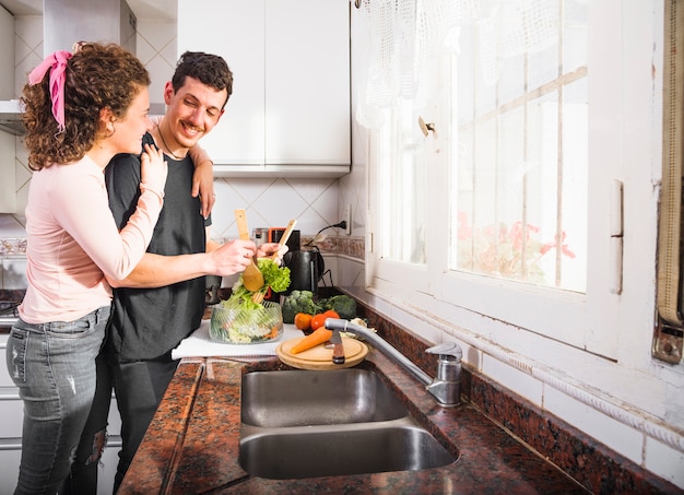 Foto gratuita pareja joven de pie cerca de la encimera de cocina preparando la comida