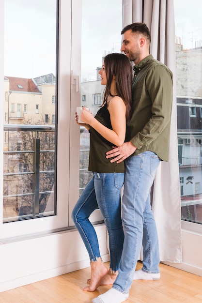 Pareja joven de pie cerca de la ventana de cristal