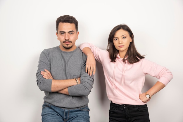 Pareja joven de pie con expresión seria.