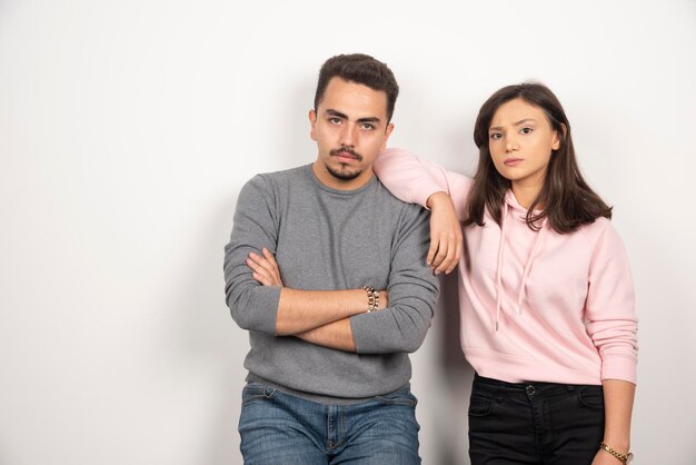 Pareja joven de pie con expresión seria.