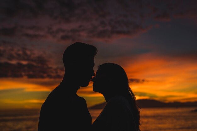 Pareja joven de pie en la orilla del mar en la noche