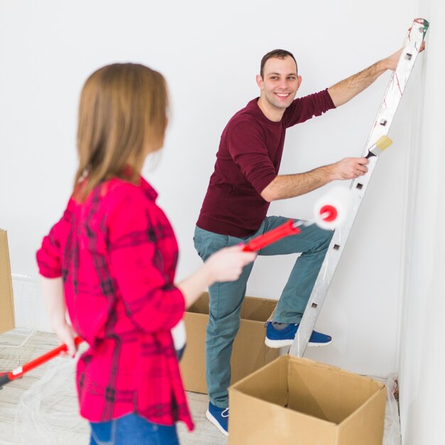 Pareja joven pintando paredes y sonriendo