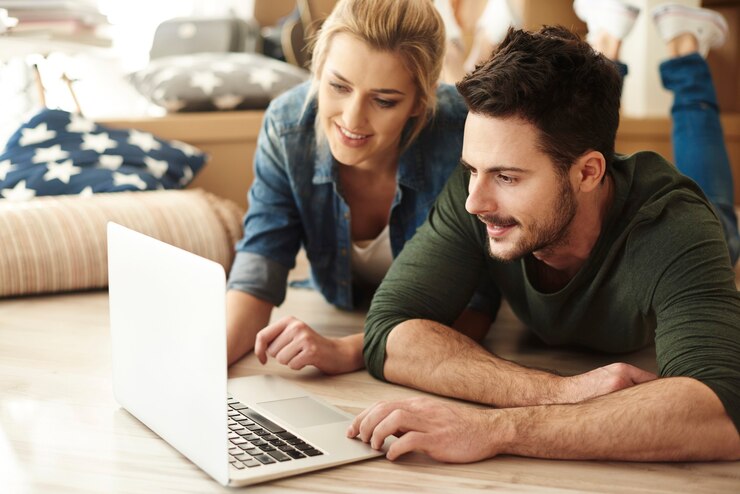 Foto gratuito pareja joven en piso nuevo usando laptop