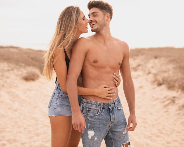 Pareja joven en la playa abrazando