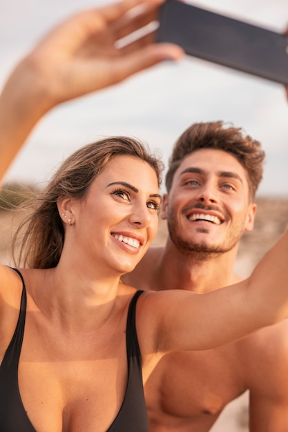 Pareja joven en la playa tomando selfie