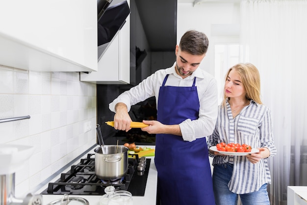 Pareja joven poniendo espaguetis en una olla con agua hervida