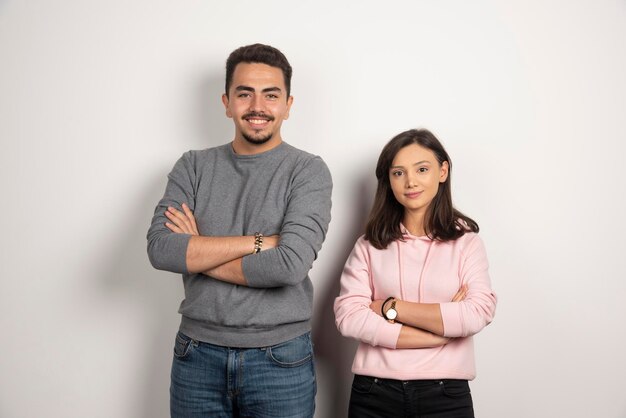 Pareja joven posando con los brazos cruzados sobre blanco.