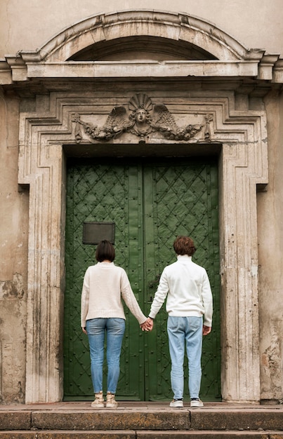 Pareja joven, posar, al lado de una puerta