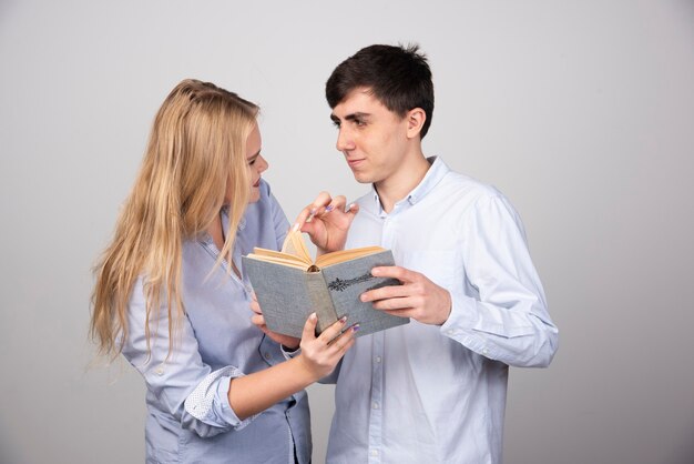 Foto gratuita pareja joven, posición, con, libro, en, fondo gris