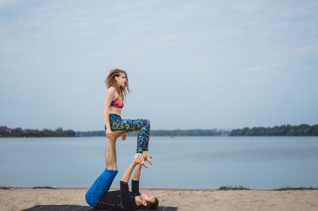 pareja joven practicando yoga en el fondo de la ciudad