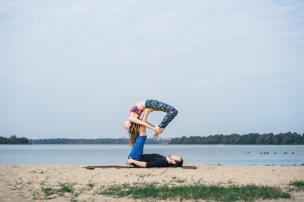 pareja joven practicando yoga en el fondo de la ciudad
