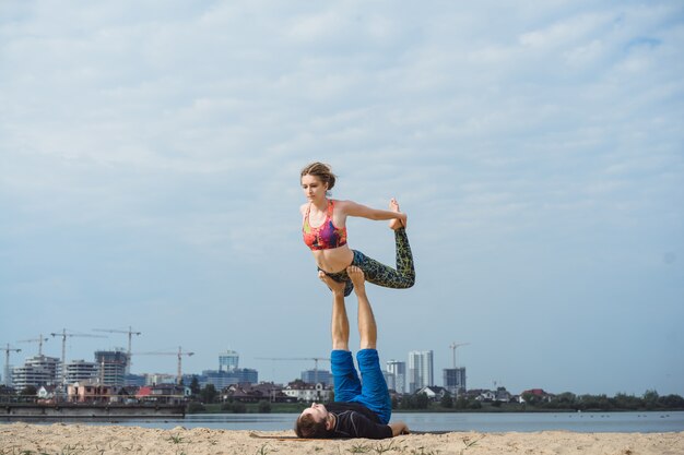 pareja joven practicando yoga en el fondo de la ciudad