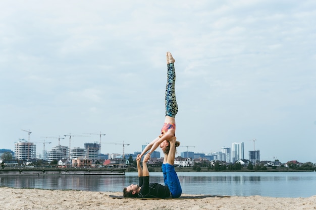 pareja joven practicando yoga en el fondo de la ciudad