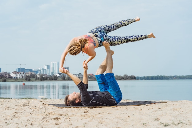 pareja joven practicando yoga en el fondo de la ciudad