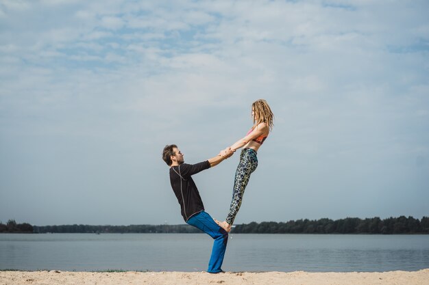 pareja joven practicando yoga en el fondo de la ciudad