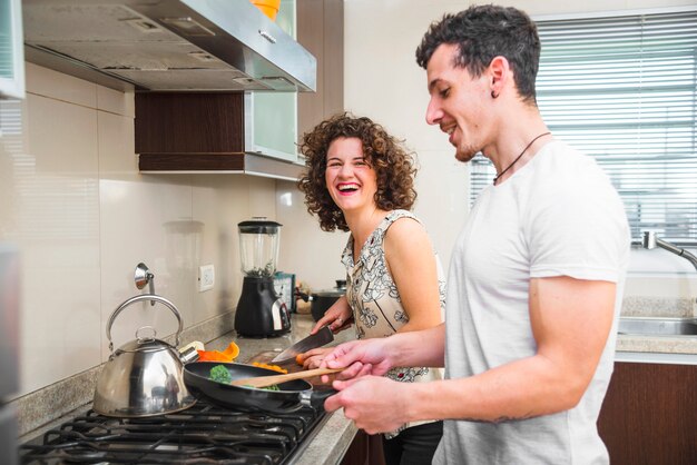 Pareja joven preparando verduras en la cocina