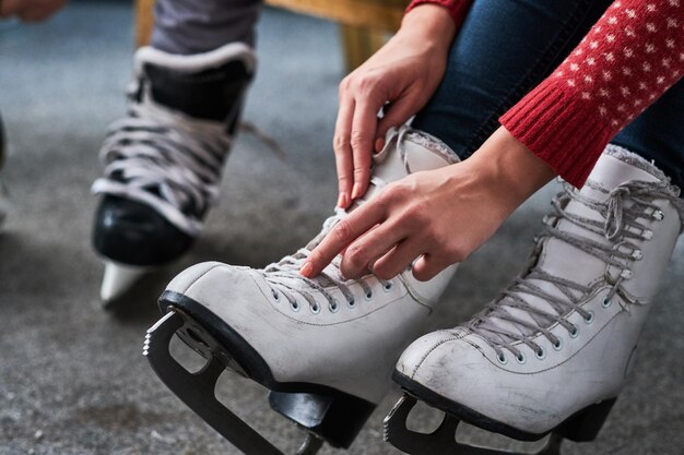 Pareja joven preparándose para patinar. Foto de primer plano de sus manos atando cordones de patines de hockey sobre hielo