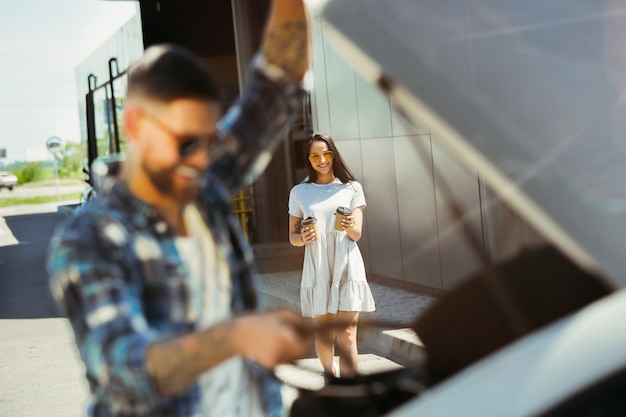 Pareja joven preparándose para un viaje de vacaciones en el coche en un día soleado