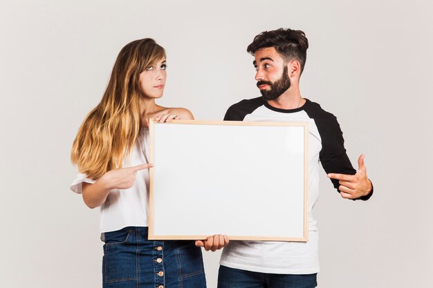 Pareja joven presentando tabla en blanco