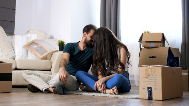 Una pareja joven que se muda a una nueva casa. Se sienta en el piso y se relaja después de desempacar.