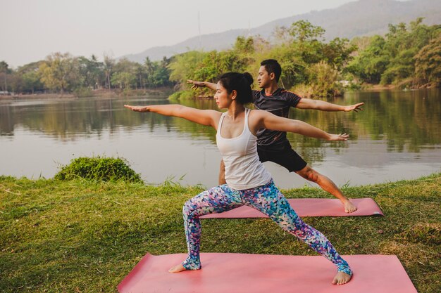 Pareja joven relajándose con el yoga en la naturaleza