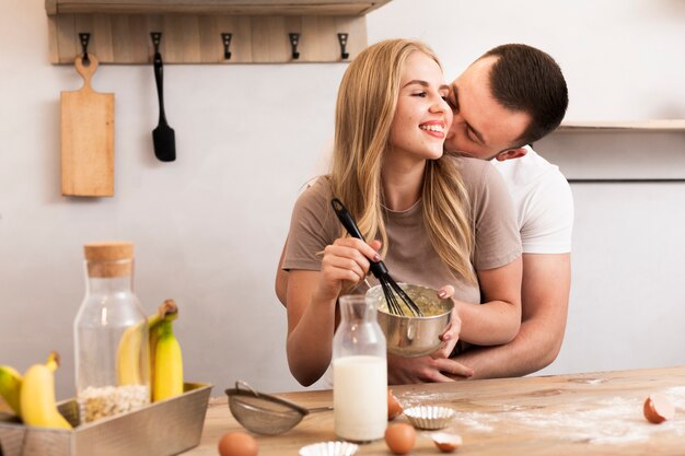 Pareja joven revuelva los huevos y la leche en el tazón