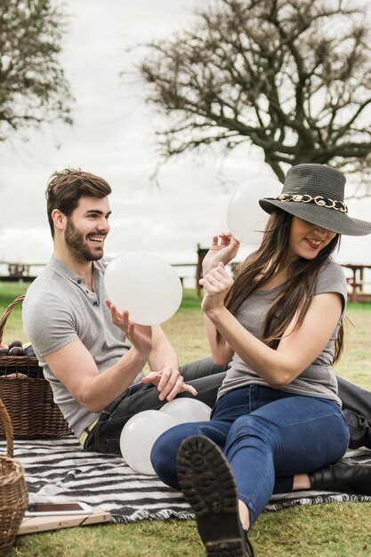 Pareja joven riéndose con globos blancos en el parque