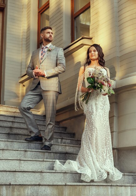 Pareja joven romántica caucásica celebrando su matrimonio en la ciudad. Tierna novia y el novio en la calle de la ciudad moderna. Familia, relación, concepto de amor. Boda contemporánea. Feliz y confiado.