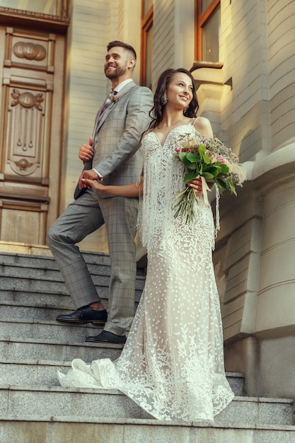 Pareja joven romántica caucásica celebrando su matrimonio en la ciudad. Tierna novia y el novio en la calle de la ciudad moderna. Familia, relación, concepto de amor