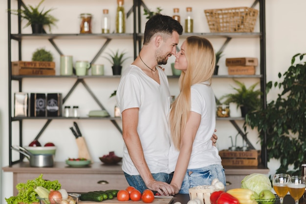 Foto gratuita pareja joven romántica de pie detrás de la barra de la cocina besos