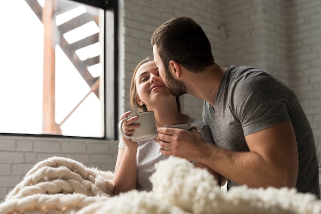 Pareja joven romántica tomando un café en la cama