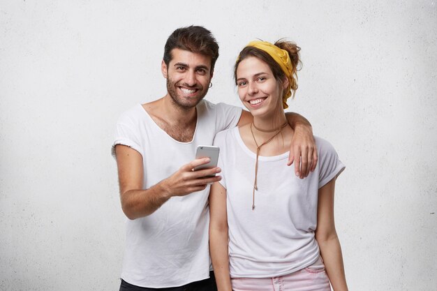 Foto gratuita pareja joven en ropa casual con smartphone en studio