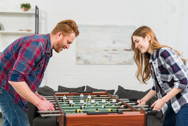 Pareja joven rubia sonriente disfrutando jugar en fútbol de mesa