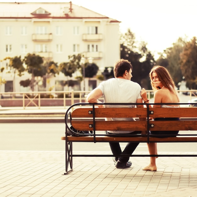 Foto gratuita pareja joven sentada en un banco en la ciudad