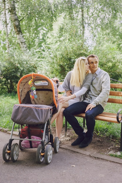Pareja joven sentada en un banco de un parque con un carrito de bebé al lado