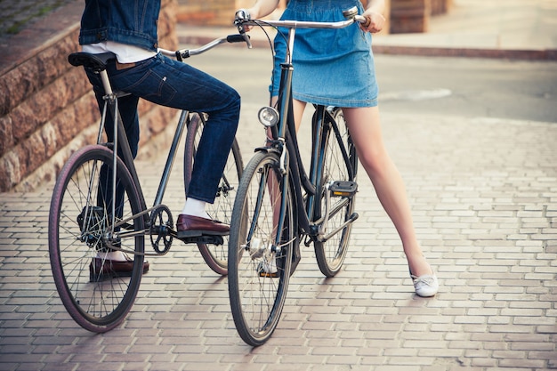 Pareja joven sentada en una bicicleta frente a la ciudad