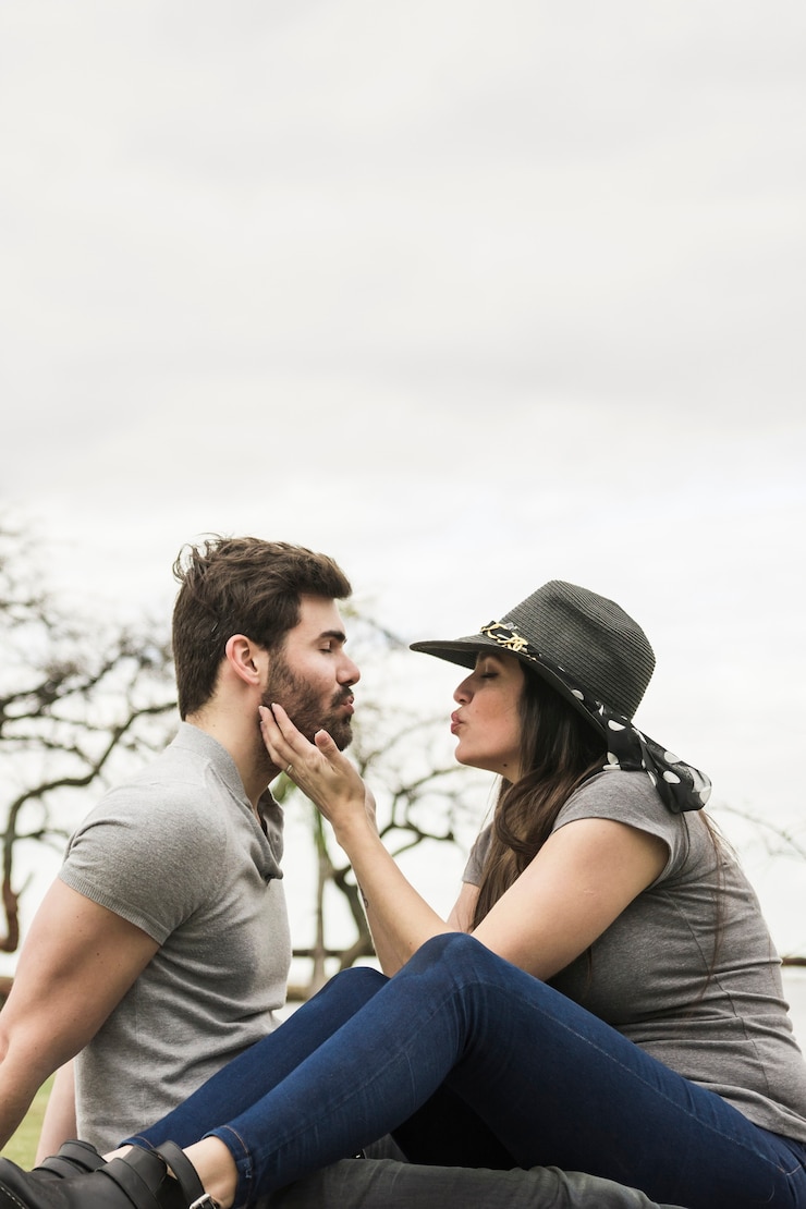 Foto gratuito pareja joven sentada cara a cara haciendo pucheros al aire libre