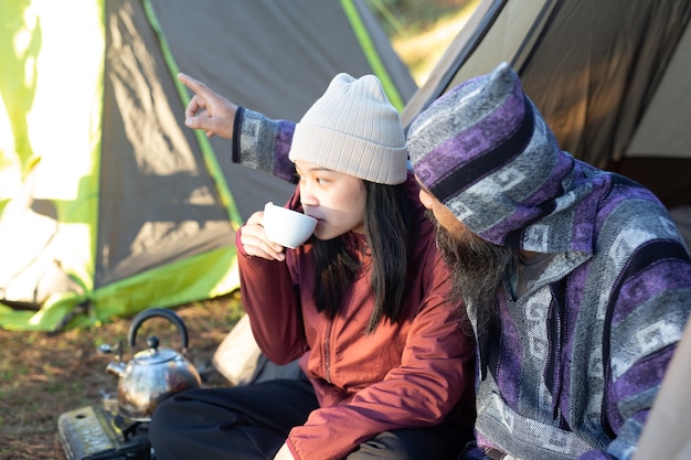 Pareja joven sentada en la carpa y tomando café por la mañana