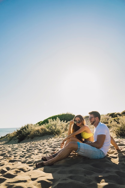 Pareja joven sentada en la playa