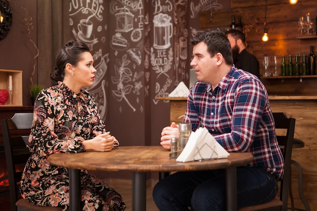 Foto gratuita pareja joven sentada en un restaurante hablando y pasando un buen rato.